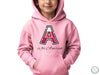 a young child wearing a pink hoodie with the letter a on it